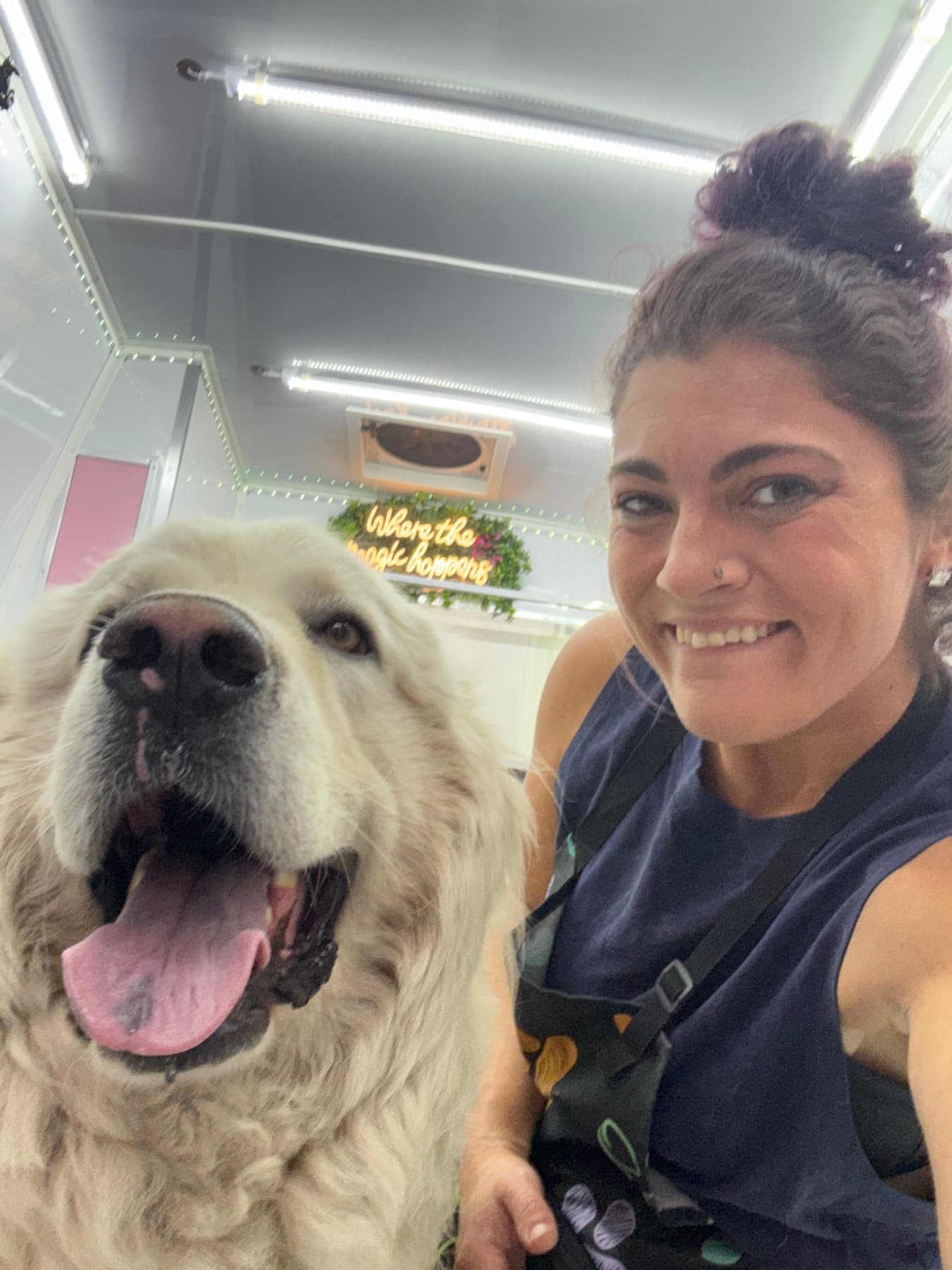 Jamie smiling with a white dog inside the Healing with Dogs mobile spa