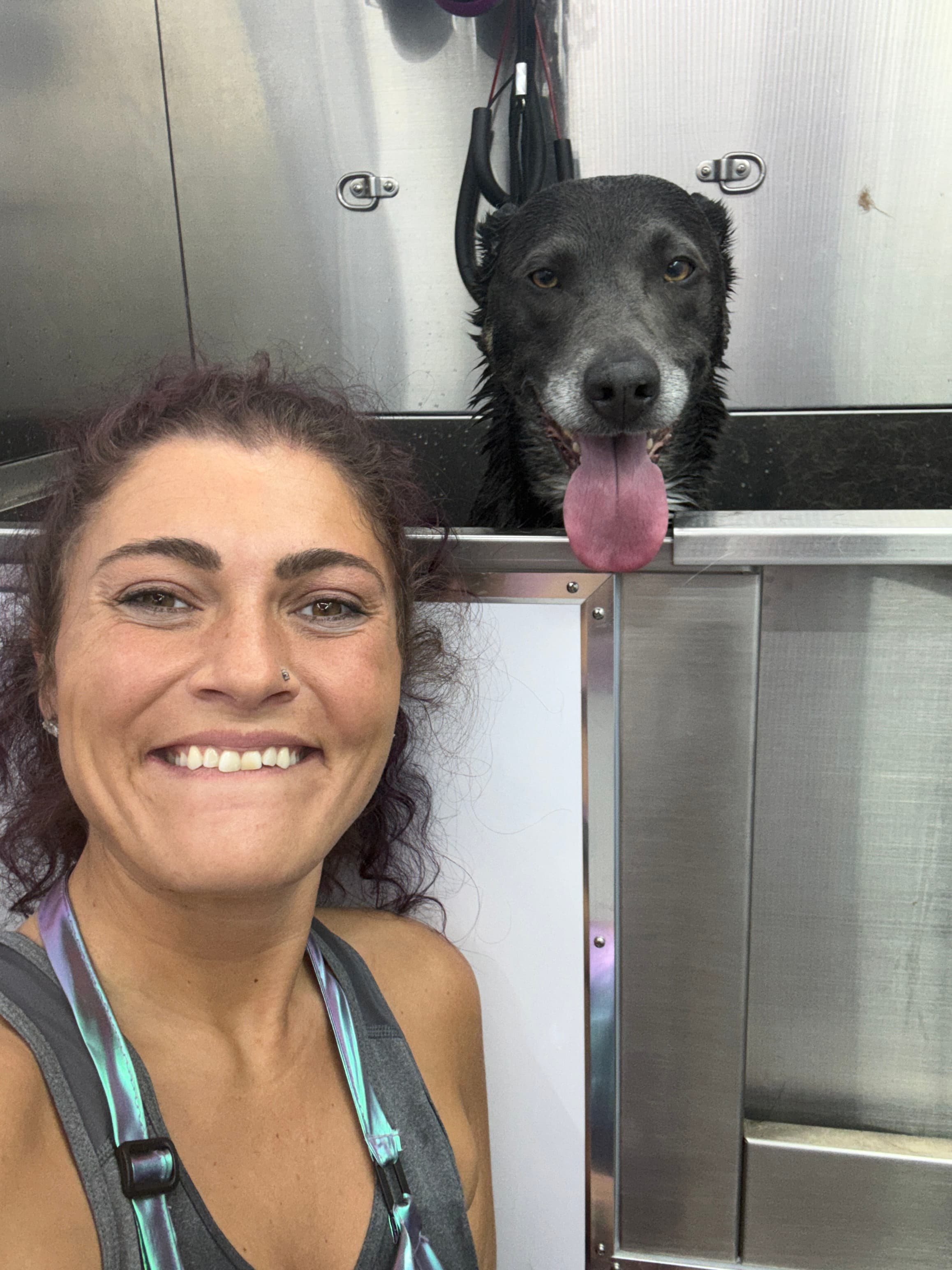 Jamie smiling beside a dog in the grooming tub